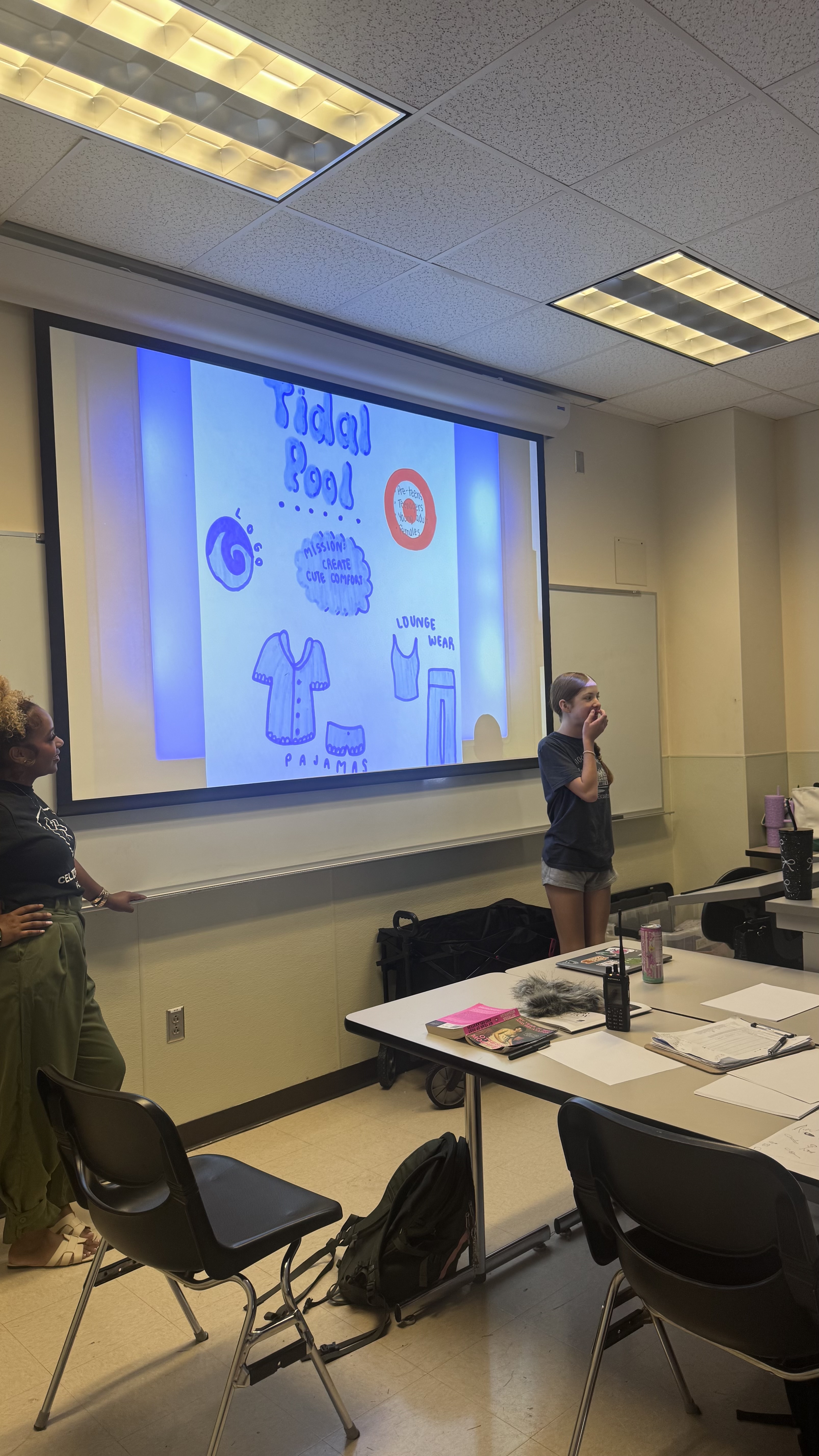 Student presents her Tidal Pool brand concept to the class while the instructor looks on